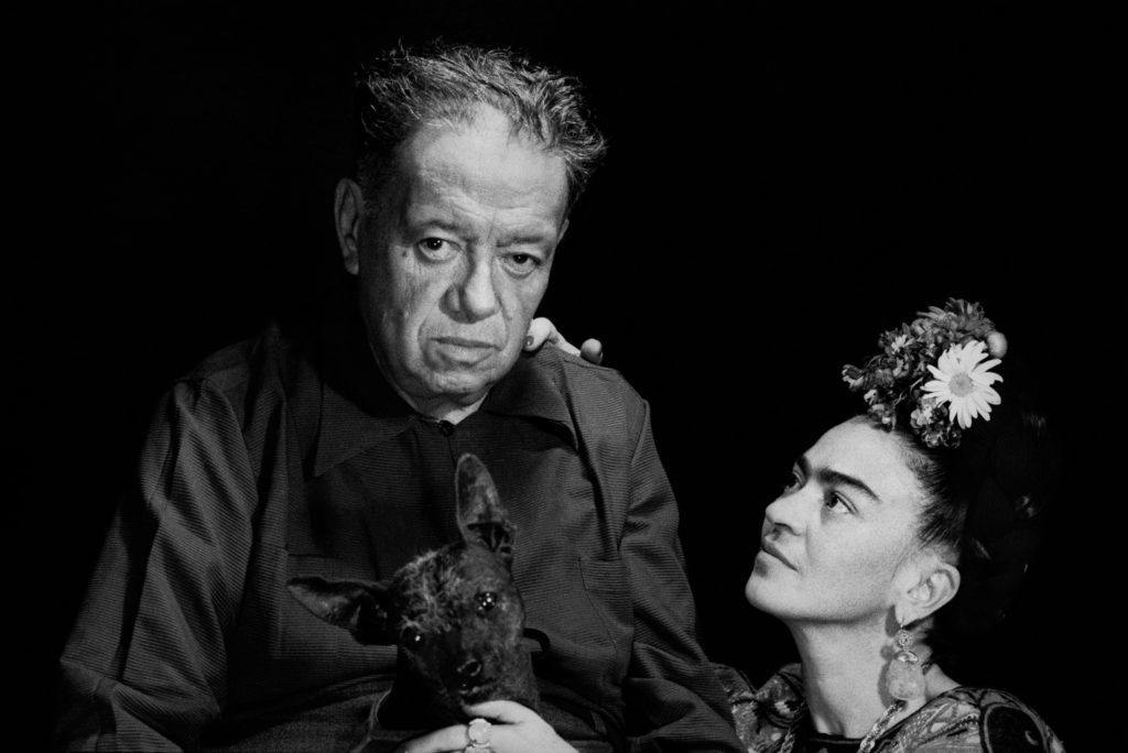 Diego Rivera and Frida Kahlo sharing a tender moment with a pet dog, illustrating the complex relationship between the renowned Mexican artists.