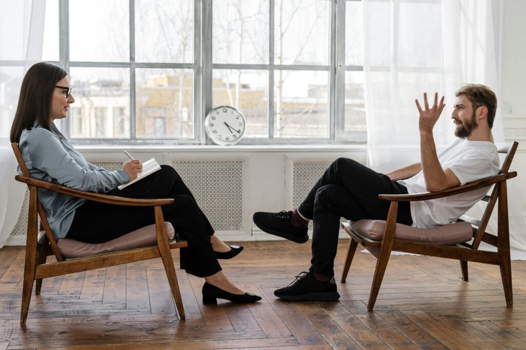 A man in a therapeutic session with a counselor, depicting the crucial step of seeking professional help for creative and mental health challenges.