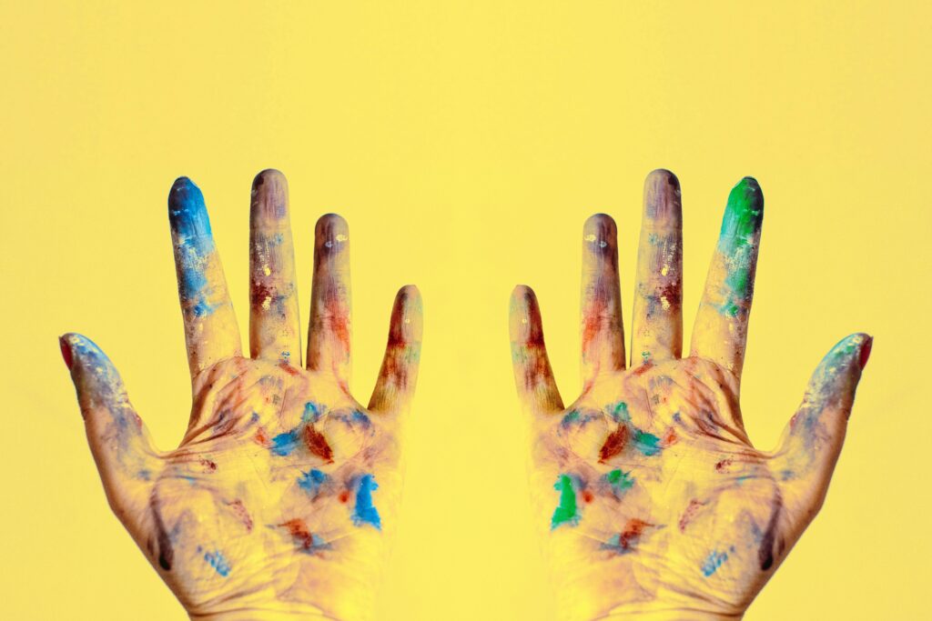 Vibrantly painted hands reaching upwards, embodying the creative awakening that overcomes art block.