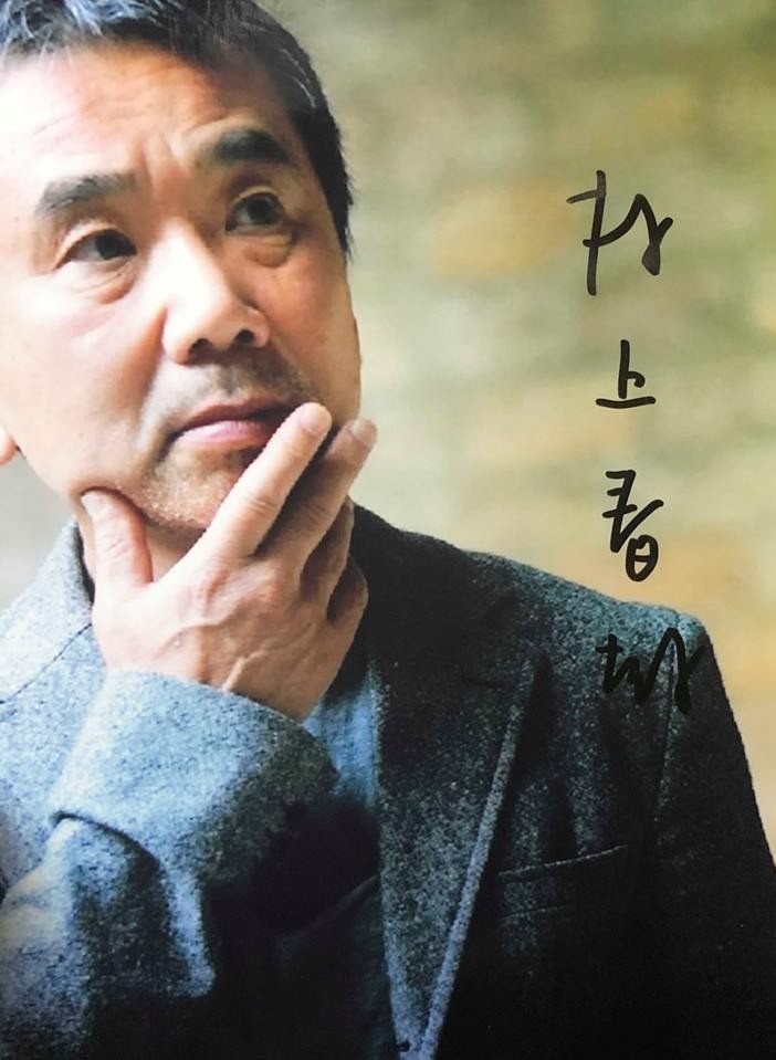 Haruki Murakami pondering thoughtfully in a grey coat.