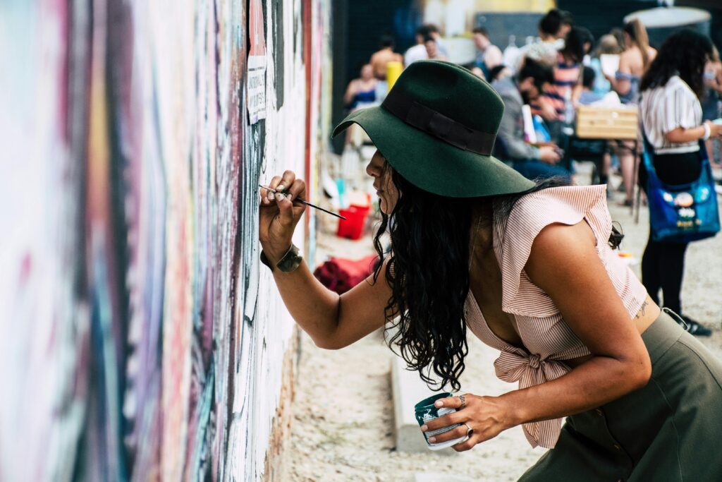 Artist painting a mural outdoors at a lively art event