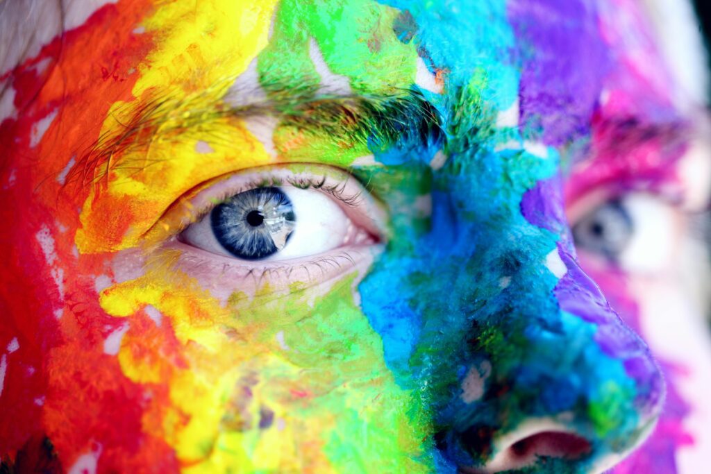 Close-up of a face painted in bright, multi-colored hues, showcasing artistic expression and creativity.
