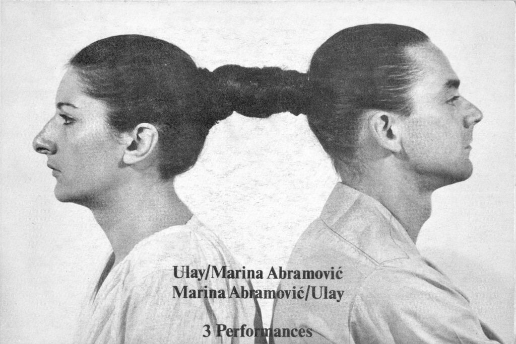 Marina Abramović and Ulay facing opposite directions with their hair tied together in a performance art piece.